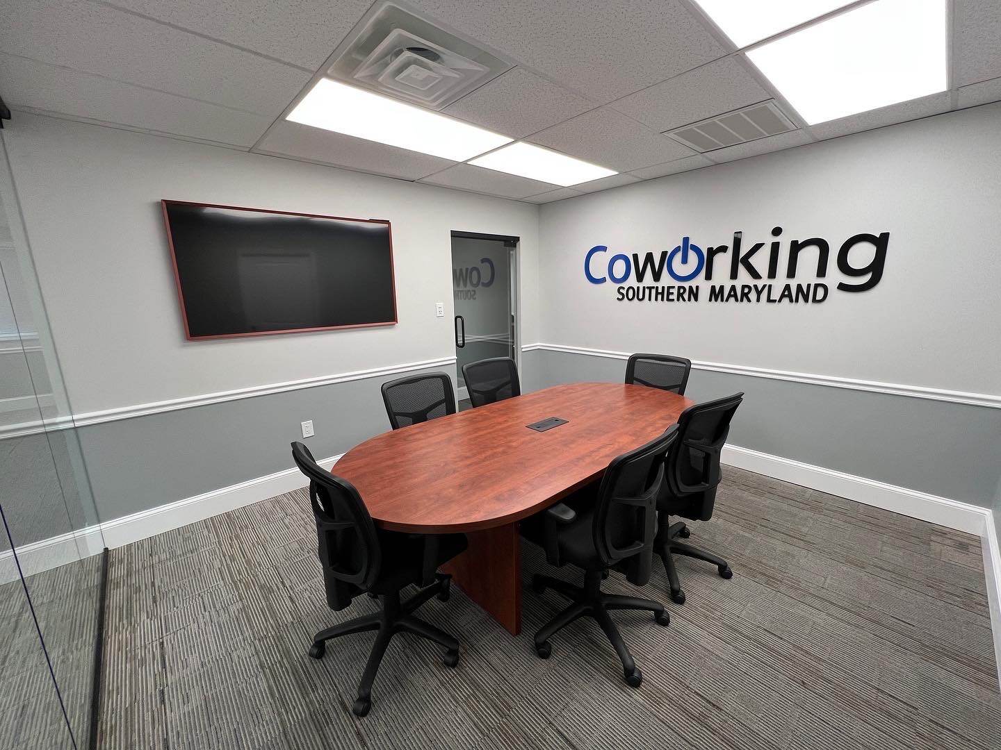 Coworking Southern Maryland conference room with table, chairs, display, and wall sign